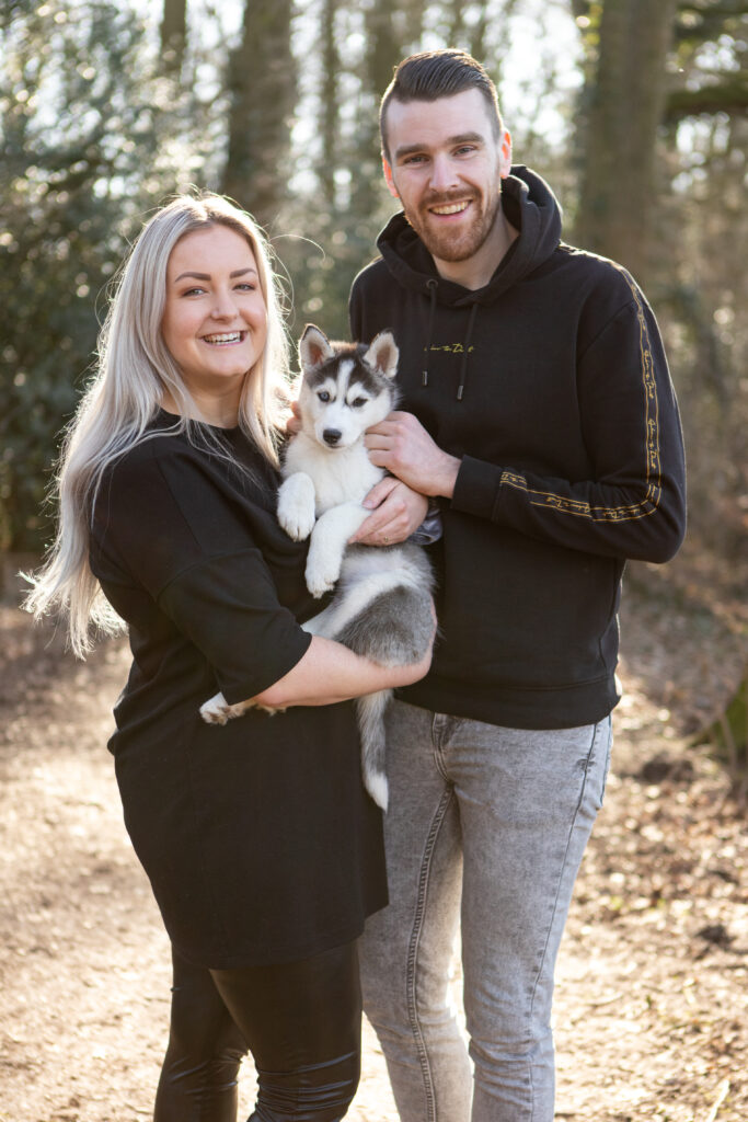 Een verliefd stel in het bos samen met hun puppy husky