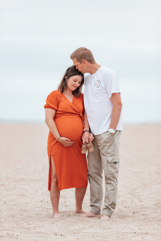 Zwangerschapsfotoshoot op het strand met babyschoenen