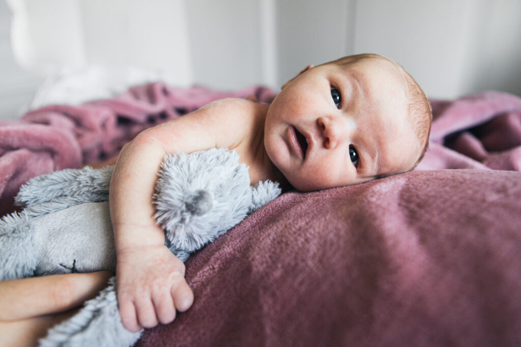 Pasgeboren baby met knuffeltje onder de arm