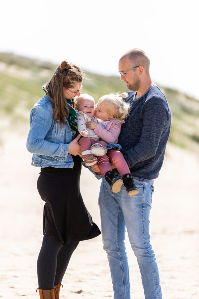 Familiefoto op het strand met twee zusjes